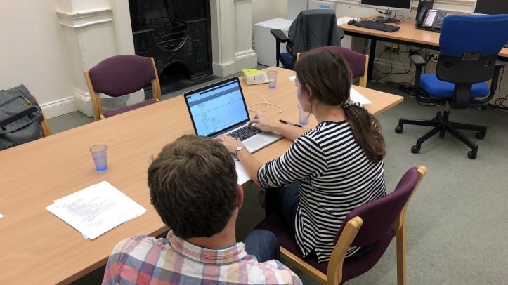 A woman using a computer whilst a man observes what she is doing