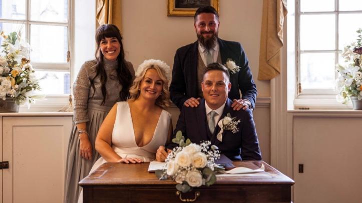 Newly wedded couple signing register with witnesses