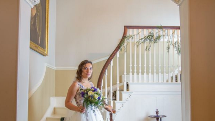 Bride with flowers standing at the bottom of a side staircase