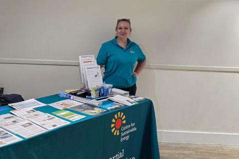 A staff member stood by a table with a range of information on.