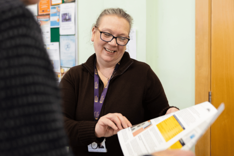 A woman wearing glasses looking at an open magazine page