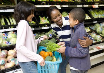 Woman and two children choosing veg at a supermarket